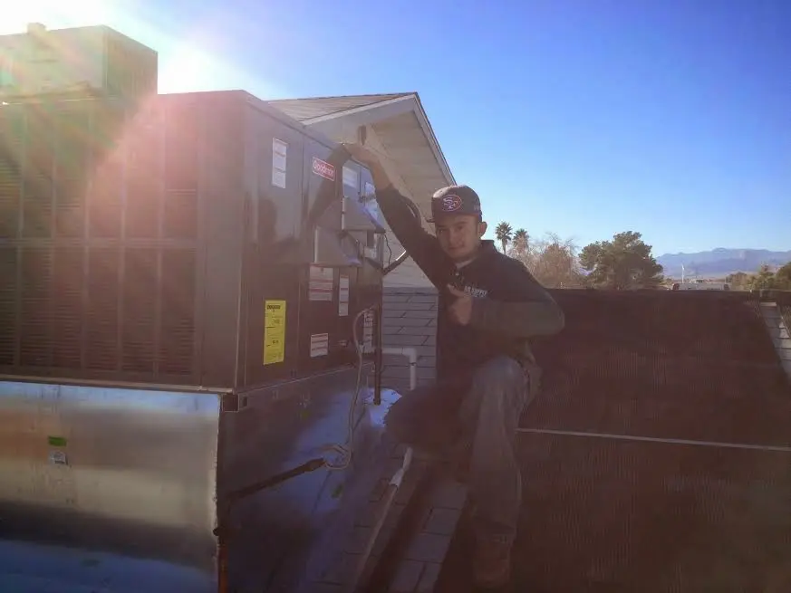 HVAC technician performing Heat Pump Repair on a rooftop unit in Robinson